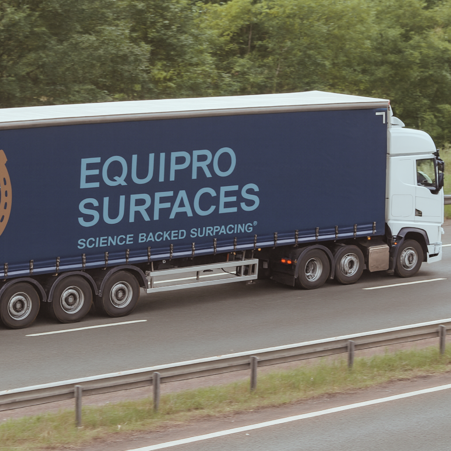 Equipro Surfaces branded lorry transporting equestrian surfacing materials on UK motorway.